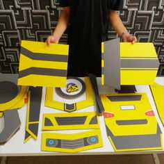 a man standing next to a table with yellow and gray paper cut out of it