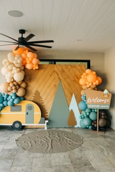 balloons are hanging from the ceiling in front of a wall with a camper and trees