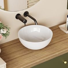 a white bowl sink sitting on top of a wooden counter next to a bathroom mirror