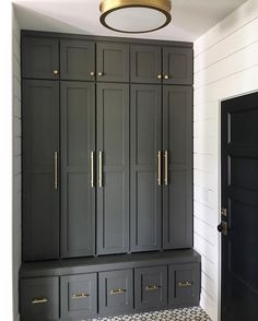 a black and white checkered floor in a room with gray cabinets, gold pulls on the doors