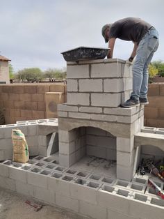 DIY Outdoor Fireplace construction with homeowner finishing the chimney with block and mortar. Standing on structure with mixing bin. Cinderblock construction with block wall behind fireplace. Outdoor Stone Fireplaces, Outside Fireplace, Diy Outdoor Fireplace, Outdoor Fireplace Designs, Backyard Remodel, Brick Oven