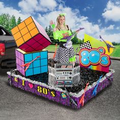 a woman standing on top of a car covered in rubiks and cubes