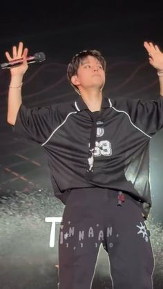 a young man is holding his hands up in the air while performing on stage at an event