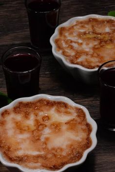 three desserts are sitting on a table with glasses next to them and one is filled with liquid