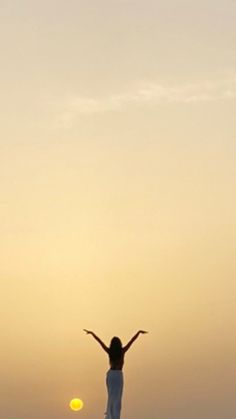 a woman standing on top of a beach next to a yellow frisbee in the air