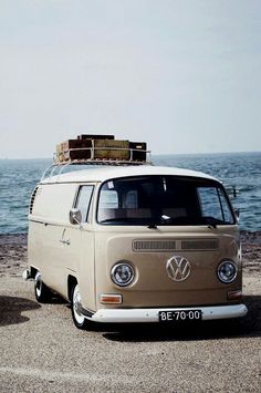 an old van parked on the beach with luggage strapped to it's roof