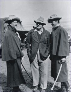 three men standing next to each other in front of an army truck and another man with a cane