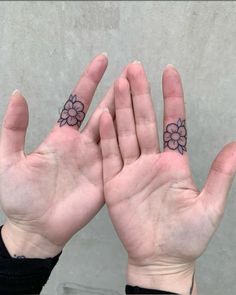 two hands with small flowers on their palms, one holding up the other's hand