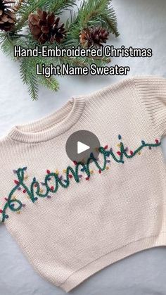 a sweater with the word merry written on it and some pine cones in the background