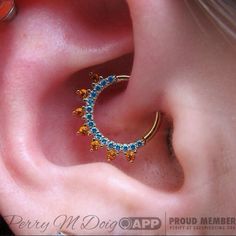 an ear piercing with blue and yellow stones on it's side, in the shape of a crescent