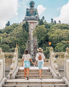 two people walking up some steps towards a statue