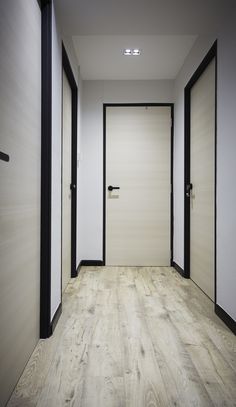 an empty hallway with white walls and black trim on the doors is seen in this image