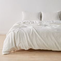 an unmade bed with white linens and pillows