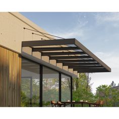 an outdoor dining area with tables and chairs under a pergolated awning over the patio