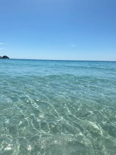 the water is crystal clear and there are rocks in the distance