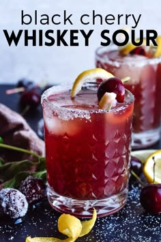 two glasses filled with black cherry whiskey sour on top of a table next to lemons and