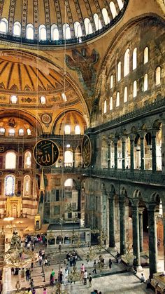 the inside of a large building with many windows and people walking around it in front of an ornate ceiling