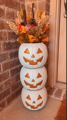 three pumpkins stacked on top of each other in front of a brick wall and door