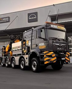 a large truck is parked in front of a building with an orange and black stripe on it