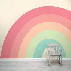 a white rocking chair sitting in front of a rainbow wall mural