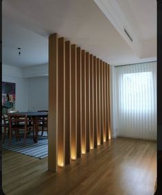 an empty room with wooden slats on the wall and floor next to a dining table