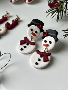 three snowmen wearing hats and scarves are sitting on a table next to christmas decorations