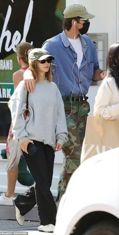 a man and woman walking down the street with headphones in their ears as they talk to each other