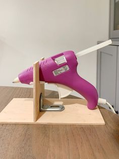 a pink hair dryer sitting on top of a wooden stand