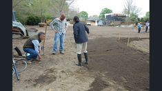 three men are working in the dirt with shovels and other people standing around them