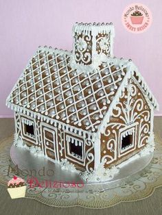 a cake that looks like a gingerbread house is on a doily with a pink wall behind it