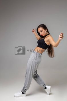 a woman in grey sweat pants and black crop top dancing