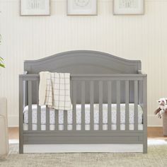 a baby crib in a room with pictures on the wall and stuffed animals beside it