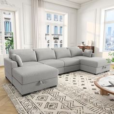 a living room with a sectional couch and coffee table in front of two large windows