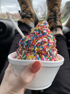 a person is holding up a cup filled with sprinkles and ice cream