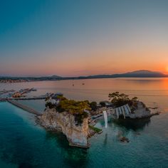 the sun is setting over an island in the ocean