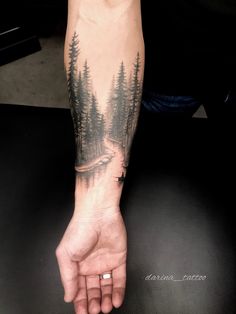 a person with a forest tattoo on their arm