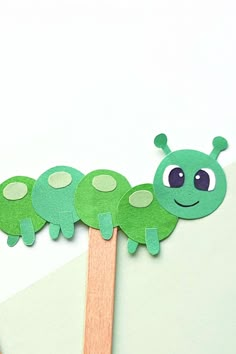 a green caterpillar on top of a wooden toothpick next to scissors