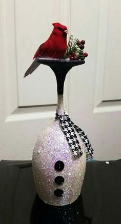 a glass vase with a snowman decoration on it and a red bird perched on top