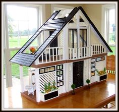 a doll house with windows and balconies on the roof is shown in front of a window