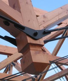 a wooden structure with metal straps attached to the top and bottom beams, against a blue sky