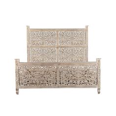 a white wooden bed frame with intricate carvings