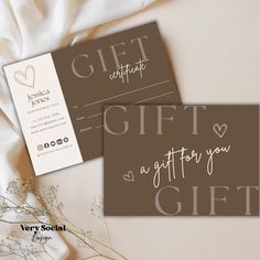 two gift cards sitting next to each other on top of a white cloth covered table