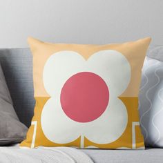 a yellow and pink flower pillow sitting on top of a couch