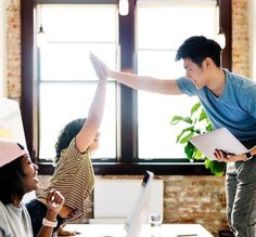 a man standing on top of a desk next to two women