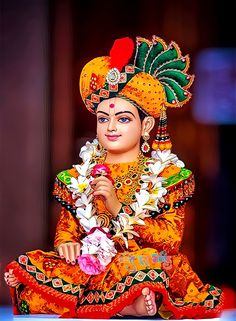 a statue of the hindu god sitting on top of a blue surface with flowers in his hand