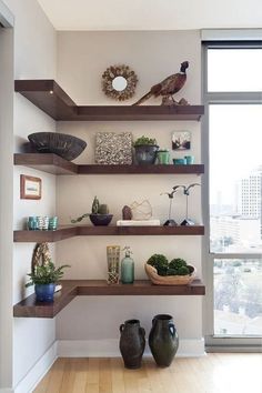 some shelves with plants and vases on them in a room near a large window