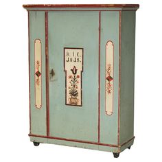 an old blue cabinet with red trimmings and painted designs on the front door