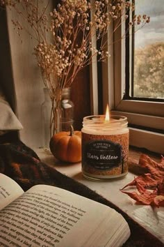 an open book sitting on top of a table next to a candle