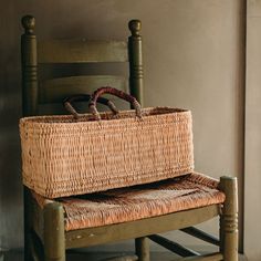 a wicker basket sitting on top of a wooden bench next to a chair and wall