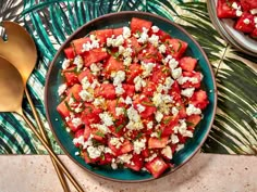 watermelon and feta salad in a bowl with gold spoons next to it